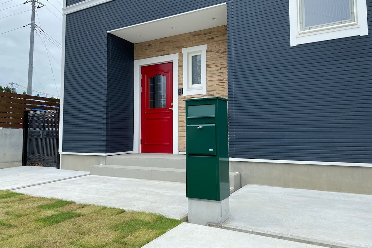 赤色の玄関ドアと似合う緑色のポスト